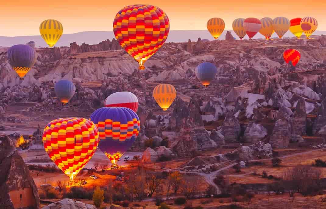 Hot air balloons floating over Cappadocia fairy chimneys at sunrise